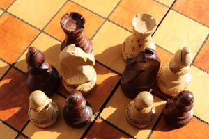 Many different figures stand on a chess board. Wood game chessboard background. photo