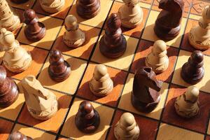 A lot of chess figures stands on a chess board. Wood game chessboard background. photo