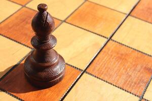 The figure of a black elephant stands on a chess board. Wood game chessboard background. photo