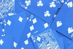Assorted play cards backdrop. Many miscellaneous jumbled blue playing cards surface. Mixed playing cards background. photo
