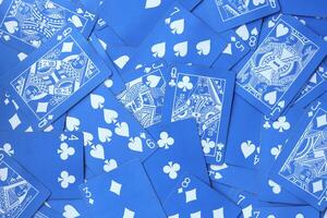 Assorted play cards backdrop. Many miscellaneous jumbled blue playing cards surface. Mixed playing cards background. photo