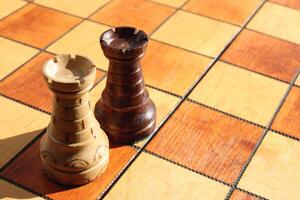Black and white rooks stand on a chess board. Wood game chessboard background. photo