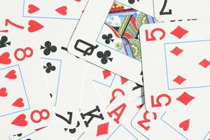 Assorted play cards backdrop. Many miscellaneous jumbled playing cards surface. Mixed playing cards background. photo