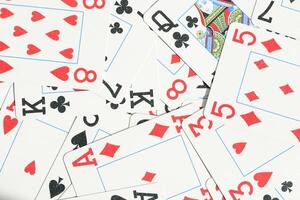 Assorted play cards backdrop. Many miscellaneous jumbled playing cards surface. Mixed playing cards background. photo