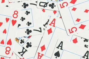 Many miscellaneous jumbled playing cards surface. Mixed playing cards background. Assorted play cards backdrop. photo