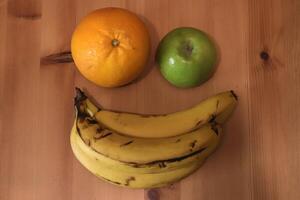 Banana with orange and apple on the table photo