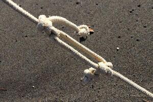 Rope with knots on sand background. Summer beach backdrop. photo