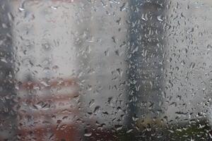 Wet window of cityscape overcast weather. Macro closeup photo