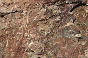 Rough bust fractured red gray detailed rock background texture. photo
