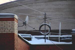 Antennas with wires on the roof of an tops building with a ladder in the background. Winter time. photo