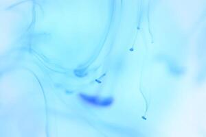 Blue Ink Drips in Clear Water. Soft Ambient Background. photo