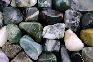 Moss agate heap jewel stones texture on white light background photo