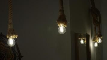 Burning stylish light bulbs decorated by ropes. Media. Stylish hanging bulbs, ethnic interior. photo