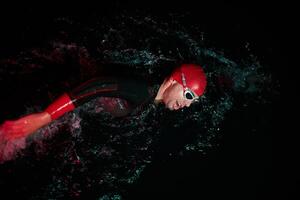 A determined professional triathlete undergoes rigorous night time training in cold waters, showcasing dedication and resilience in preparation for an upcoming triathlon swim competition photo