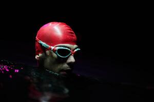 A determined professional triathlete undergoes rigorous night time training in cold waters, showcasing dedication and resilience in preparation for an upcoming triathlon swim competition photo