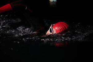 A determined professional triathlete undergoes rigorous night time training in cold waters, showcasing dedication and resilience in preparation for an upcoming triathlon swim competition photo