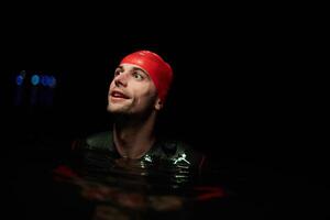 A determined professional triathlete undergoes rigorous night time training in cold waters, showcasing dedication and resilience in preparation for an upcoming triathlon swim competition photo