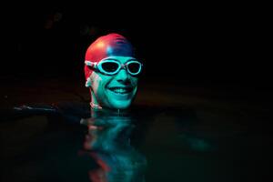 Authentic triathlete swimmer having a break during hard training on night neon gel light photo
