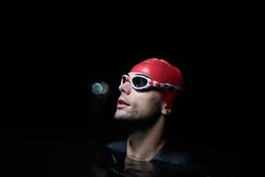 A determined professional triathlete undergoes rigorous night time training in cold waters, showcasing dedication and resilience in preparation for an upcoming triathlon swim competition photo