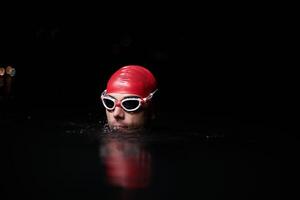 A determined professional triathlete undergoes rigorous night time training in cold waters, showcasing dedication and resilience in preparation for an upcoming triathlon swim competition photo