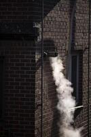 Steam coming out of a central heating flue on a house wall in South Korea. photo