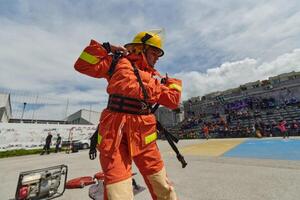 In a dynamic display of synchronized teamwork, firefighters hustle to carry, connect, and deploy firefighting hoses with precision, showcasing their intensive training and readiness for challenging photo