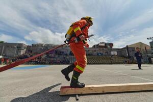 In a dynamic display of synchronized teamwork, firefighters hustle to carry, connect, and deploy firefighting hoses with precision, showcasing their intensive training and readiness for challenging photo