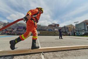 In a dynamic display of synchronized teamwork, firefighters hustle to carry, connect, and deploy firefighting hoses with precision, showcasing their intensive training and readiness for challenging photo