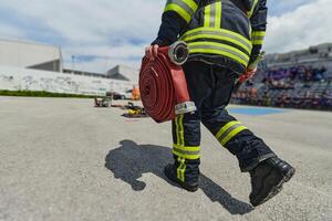 In a dynamic display of synchronized teamwork, firefighters hustle to carry, connect, and deploy firefighting hoses with precision, showcasing their intensive training and readiness for challenging photo