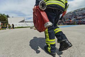 In a dynamic display of synchronized teamwork, firefighters hustle to carry, connect, and deploy firefighting hoses with precision, showcasing their intensive training and readiness for challenging photo