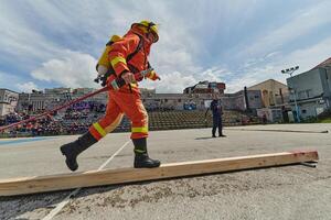 In a dynamic display of synchronized teamwork, firefighters hustle to carry, connect, and deploy firefighting hoses with precision, showcasing their intensive training and readiness for challenging photo