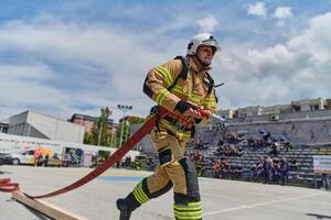 In a dynamic display of synchronized teamwork, firefighters hustle to carry, connect, and deploy firefighting hoses with precision, showcasing their intensive training and readiness for challenging photo