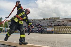 In a dynamic display of synchronized teamwork, firefighters hustle to carry, connect, and deploy firefighting hoses with precision, showcasing their intensive training and readiness for challenging photo