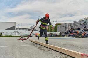 In a dynamic display of synchronized teamwork, firefighters hustle to carry, connect, and deploy firefighting hoses with precision, showcasing their intensive training and readiness for challenging photo