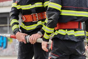 In a dynamic display of synchronized teamwork, firefighters hustle to carry, connect, and deploy firefighting hoses with precision, showcasing their intensive training and readiness for challenging photo