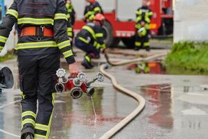 In a dynamic display of synchronized teamwork, firefighters hustle to carry, connect, and deploy firefighting hoses with precision, showcasing their intensive training and readiness for challenging photo