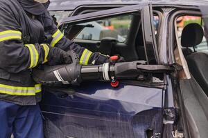 A dedicated team of professional firefighters employs specialized tools to cut and break through vehicle wreckage, showcasing their skilled collaboration and swift response in rescuing individuals photo