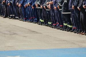 A group of firefighters lined up, saluting the flag, applauding in solidarity, and gearing up for intensive training sessions, showcasing their unwavering commitment to service and teamwork. photo