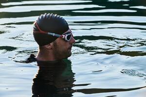 A triathlete finds serene rejuvenation in a lake, basking in the tranquility of the water after an intense training session photo
