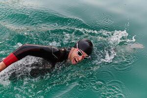 A professional triathlete trains with unwavering dedication for an upcoming competition at a lake, emanating a sense of athleticism and profound commitment to excellence. photo