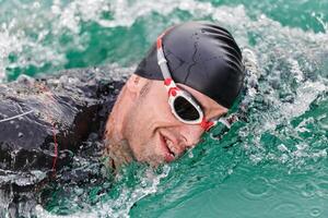 A professional triathlete trains with unwavering dedication for an upcoming competition at a lake, emanating a sense of athleticism and profound commitment to excellence. photo