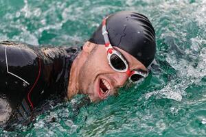 A professional triathlete trains with unwavering dedication for an upcoming competition at a lake, emanating a sense of athleticism and profound commitment to excellence. photo