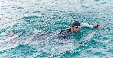 A professional triathlete trains with unwavering dedication for an upcoming competition at a lake, emanating a sense of athleticism and profound commitment to excellence. photo