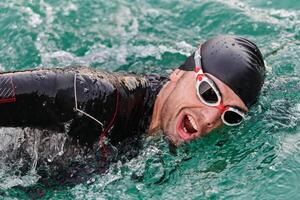 A professional triathlete trains with unwavering dedication for an upcoming competition at a lake, emanating a sense of athleticism and profound commitment to excellence. photo