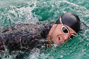A professional triathlete trains with unwavering dedication for an upcoming competition at a lake, emanating a sense of athleticism and profound commitment to excellence. photo
