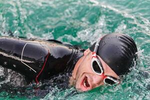 A professional triathlete trains with unwavering dedication for an upcoming competition at a lake, emanating a sense of athleticism and profound commitment to excellence. photo
