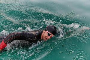 A professional triathlete trains with unwavering dedication for an upcoming competition at a lake, emanating a sense of athleticism and profound commitment to excellence. photo