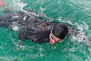 A professional triathlete trains with unwavering dedication for an upcoming competition at a lake, emanating a sense of athleticism and profound commitment to excellence. photo