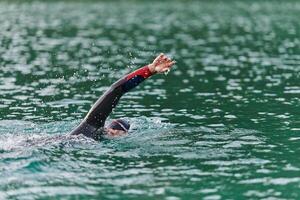 A professional triathlete trains with unwavering dedication for an upcoming competition at a lake, emanating a sense of athleticism and profound commitment to excellence. photo
