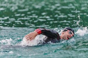 A professional triathlete trains with unwavering dedication for an upcoming competition at a lake, emanating a sense of athleticism and profound commitment to excellence. photo